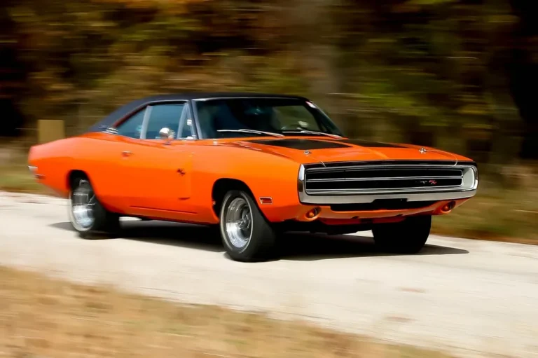 Orange Dodge Charger R/T muscle car driving on a gravel road