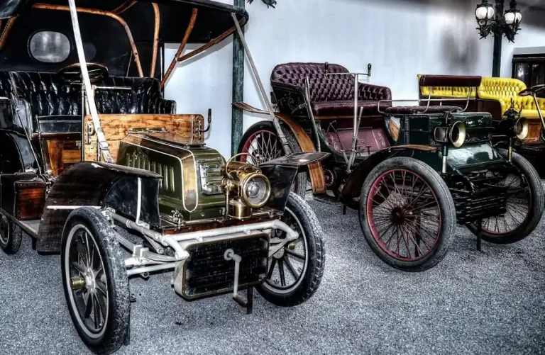Early motor cars with leather seats and spoked wheels on display in an automobile museum