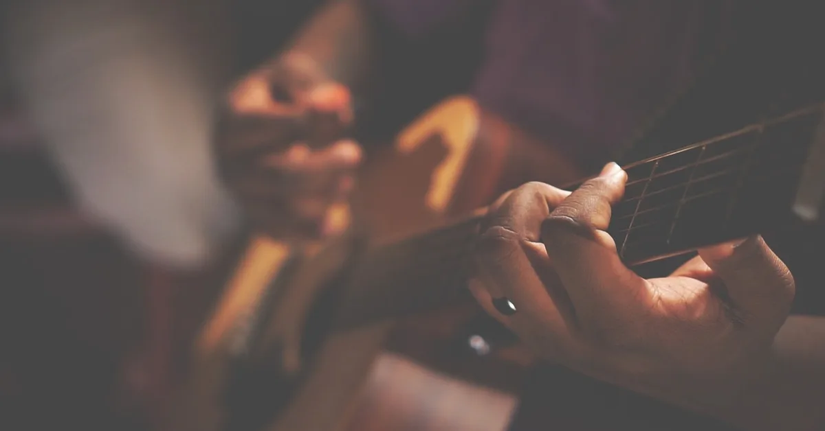 Hands playing an acoustic guitar, the instrument behind Fast Car