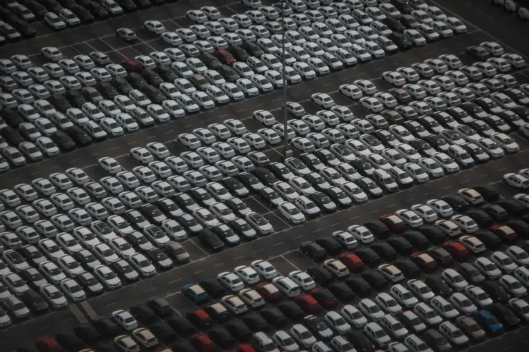 Aerial view of rows of new cars parked in a large vehicle lot