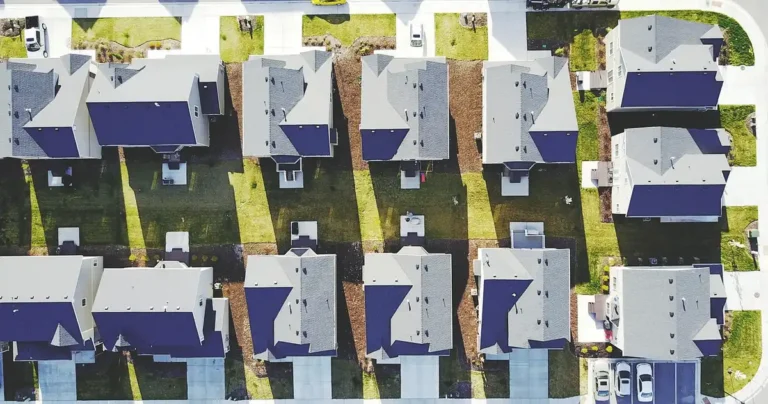 Aerial view of a suburban street with houses, driveways and parked cars