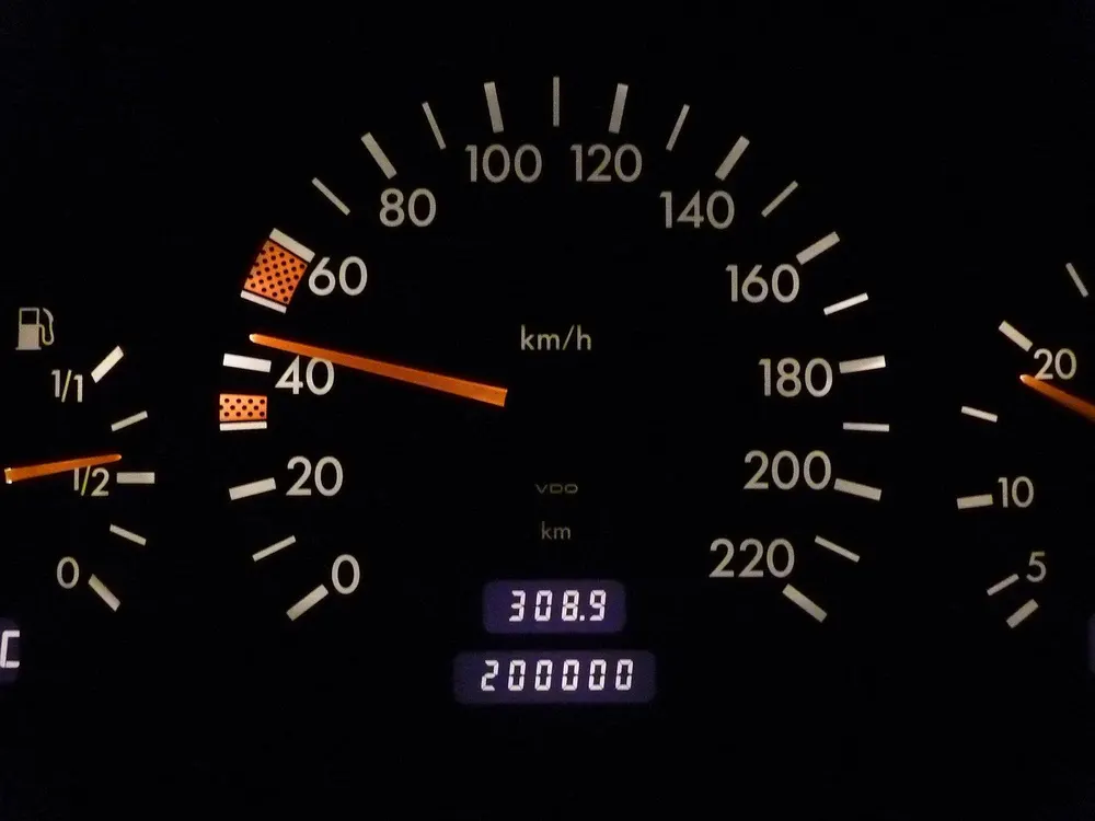 Analog car speedometer and odometer on a dark dashboard