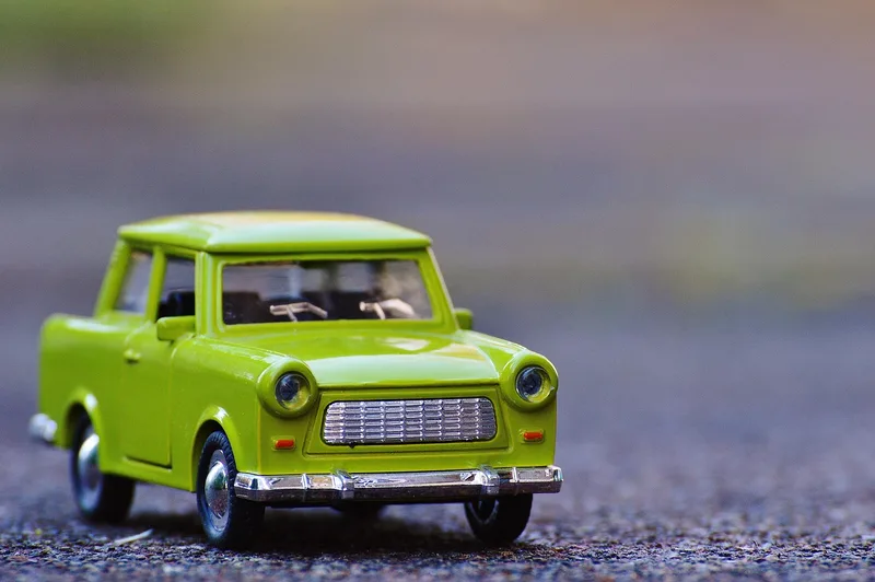 Bright green toy car with a chrome bumper on a gravel surface
