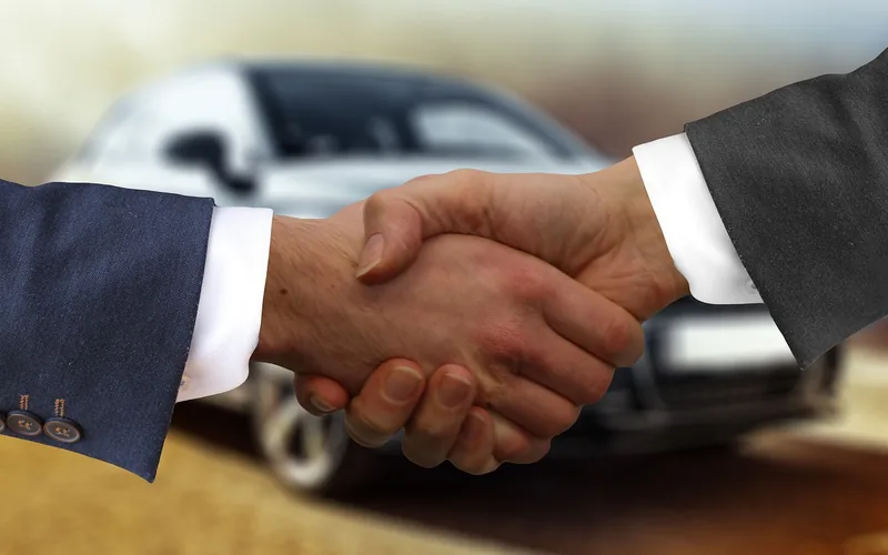 Buyer and dealer shaking hands after agreeing on a negotiated car price Buyer and dealer shaking hands after agreeing on a negotiated car price
