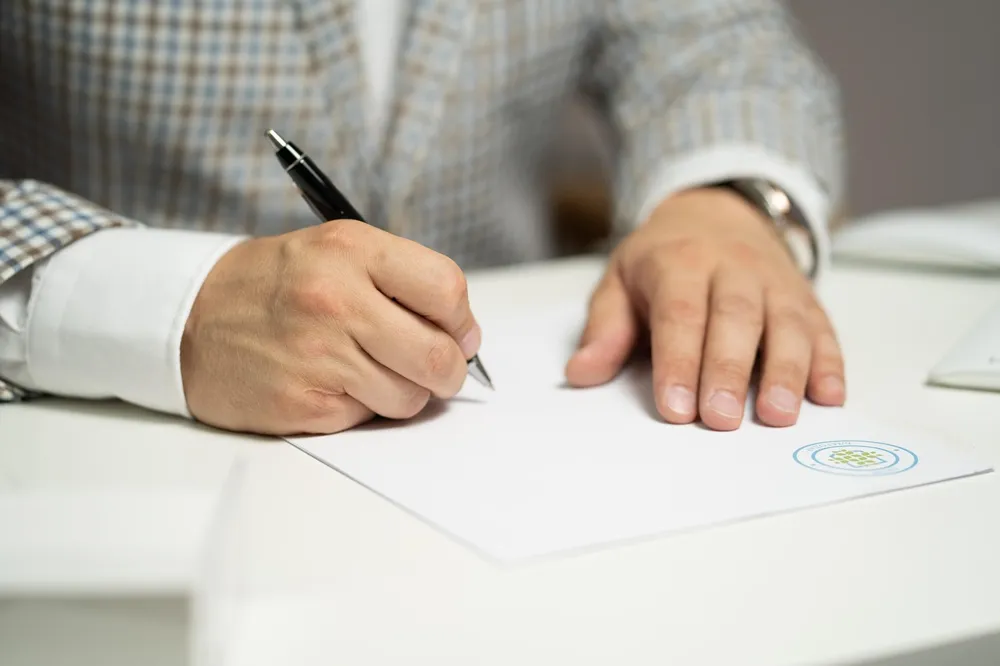 Person signing a document with a pen at a desk