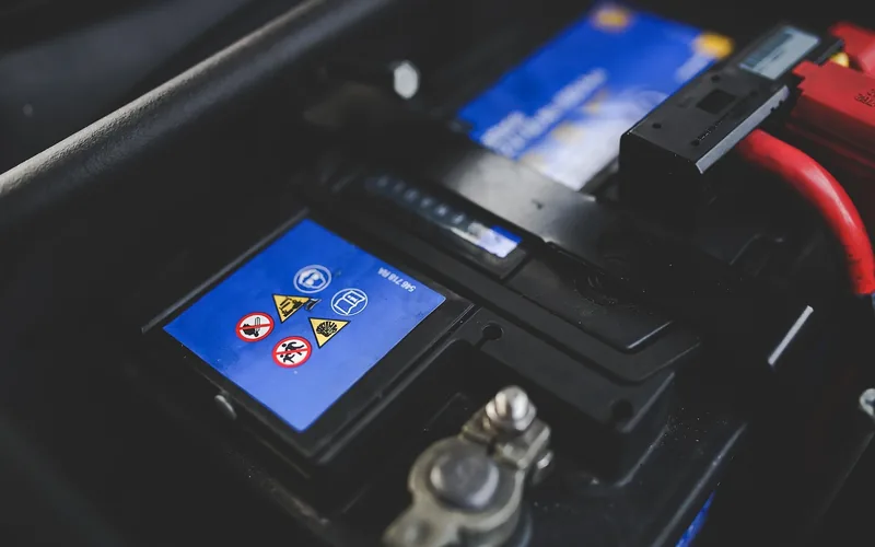 car battery with safety warning labels near the terminals