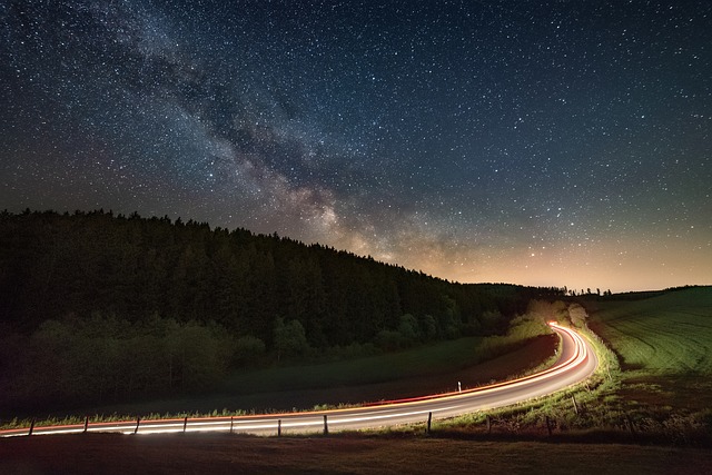 A car driving with headlights on a dark road at night, when deer-vehicle collisions are most common