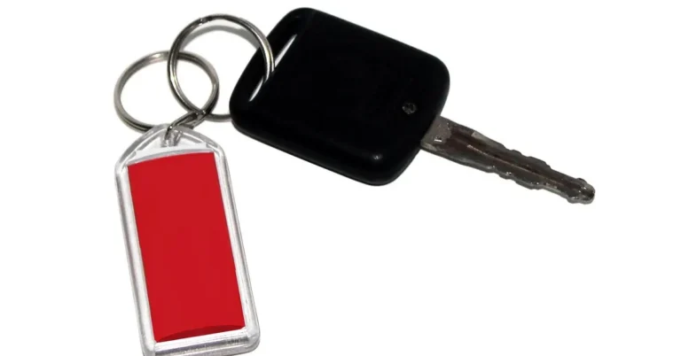 Car key with a black plastic head and a red tag on a split ring