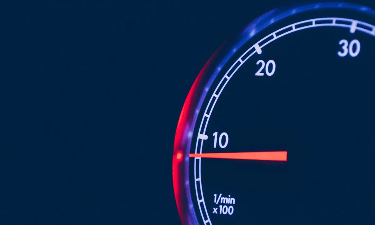 Close-up of a car tachometer dial with a needle and a scale labelled 1/min x100