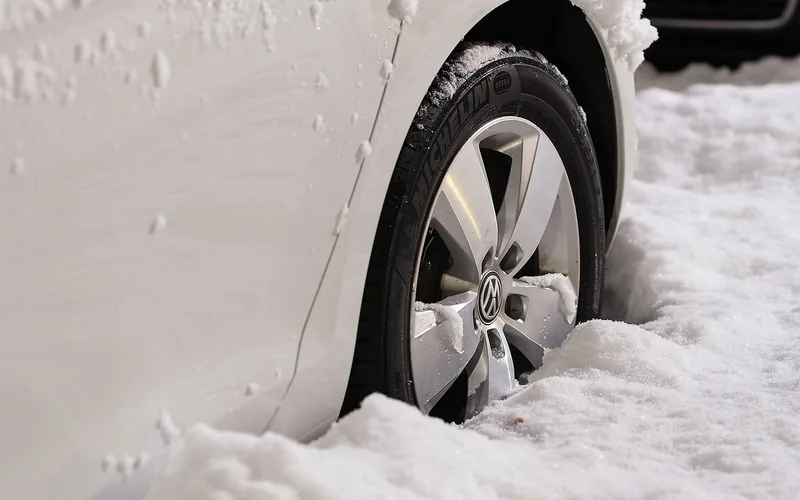 Car tire buried in packed snow with visible ruts from spinning Car tire buried in packed snow with visible ruts from spinning