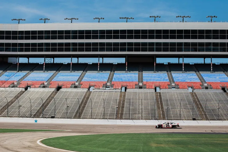 Empty race track grandstand with a single stock car on the track