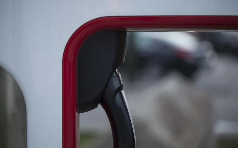 A charging connector hanging on a red-trimmed charging post