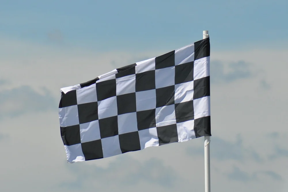 Checkered flag waving at an IndyCar race, symbolizing the 2026 season finale at Laguna Seca