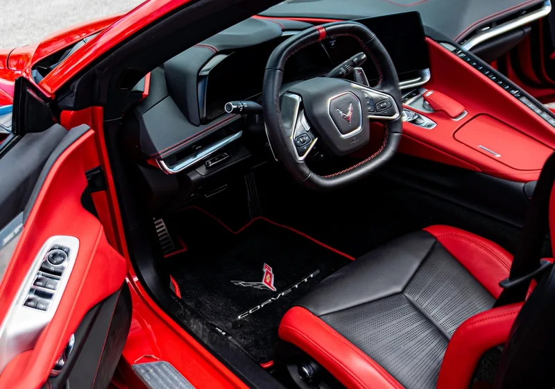 Red and black Corvette interior with steering wheel and floor mat