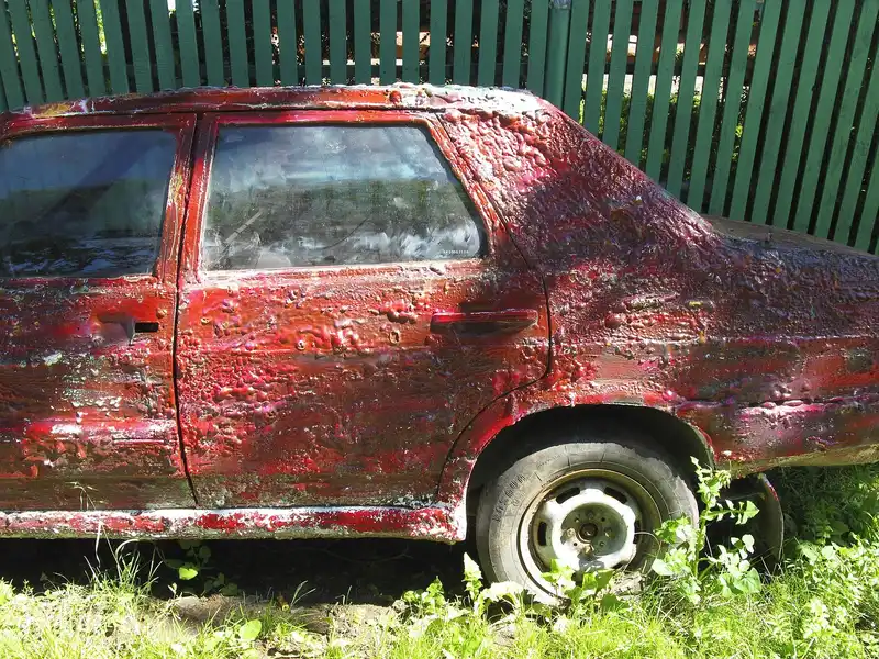 Car side panel with blistered and flaking red paint
