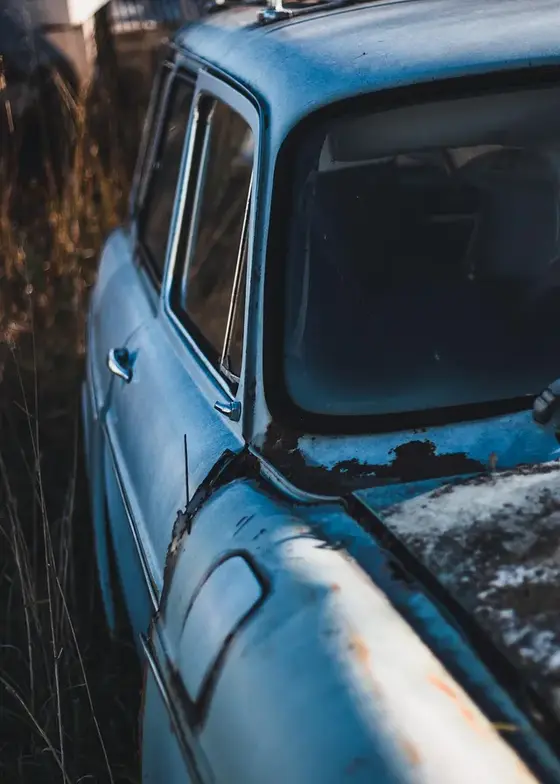 Old blue car hood and fender with flaking paint and rust