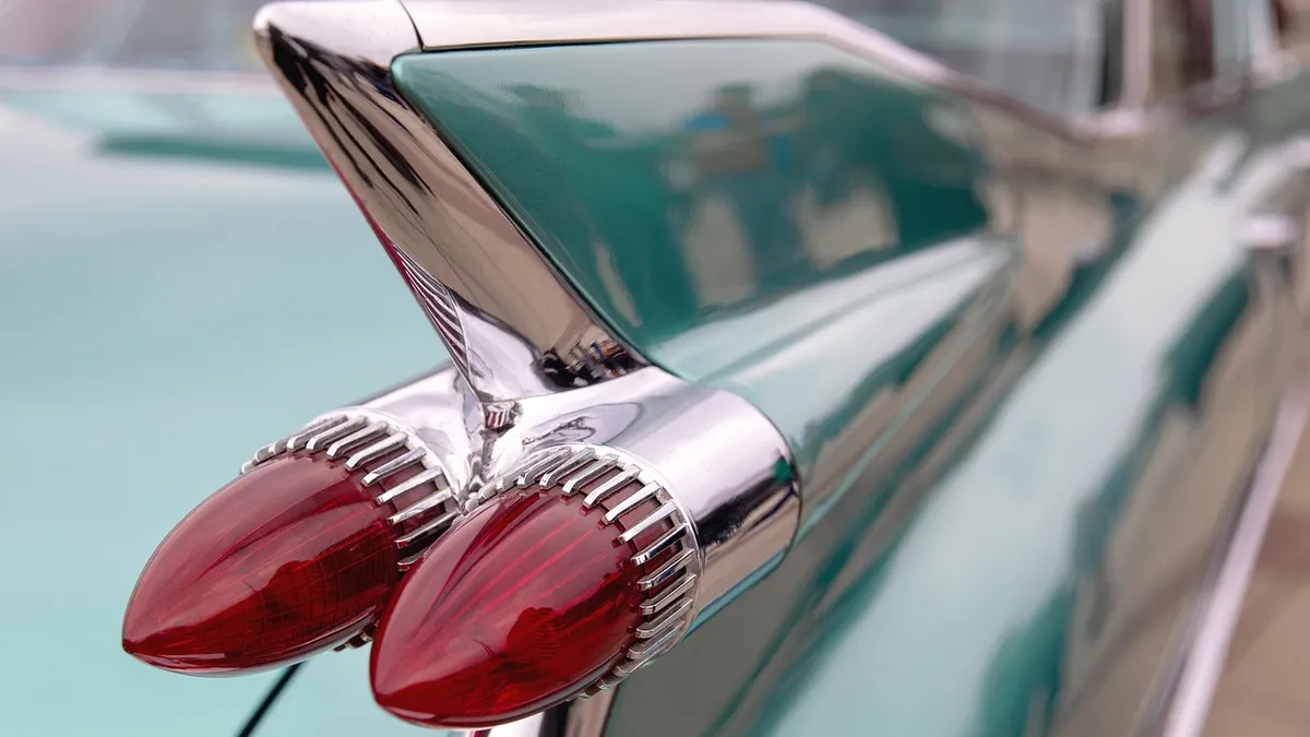 Chrome tail fin and bullet-shaped red tail lamps on a teal vintage car