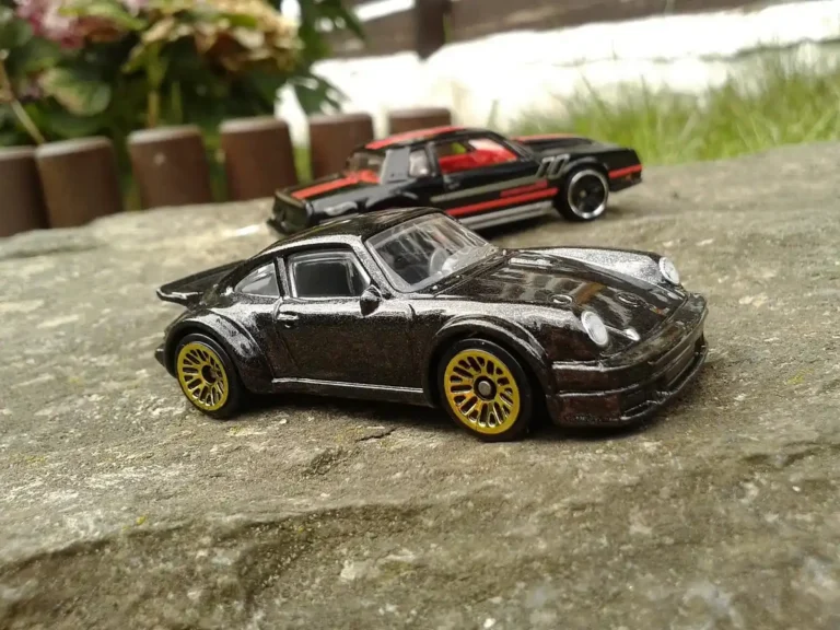 Two small black die-cast toy cars on a stone surface outdoors