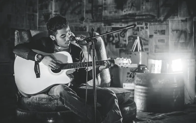 Fast Car was written in the folk-blues singer-songwriter tradition Acoustic guitarist performing on stage, similar to the folk-blues style Tracy Chapman used on Fast Car