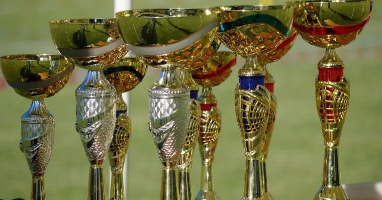 Row of gold trophy cups lined up on a table outdoors