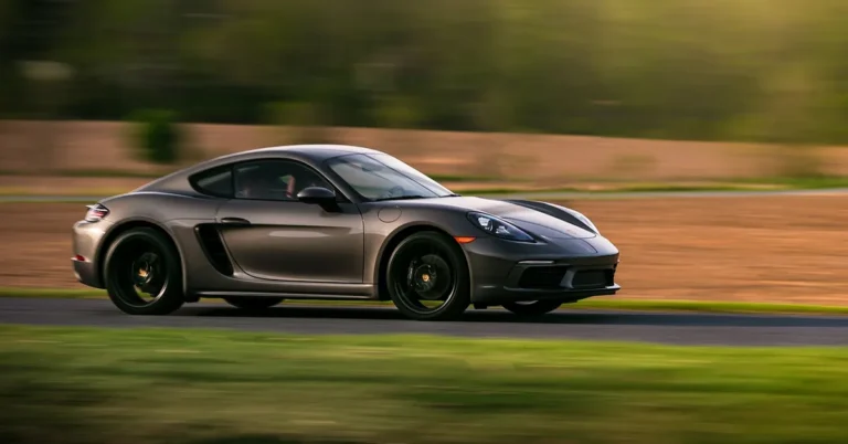 Grey two-door sports coupe driving at speed on a country road