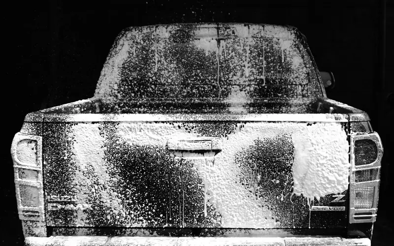 white car being hand washed with soap and foam at a car wash white car being hand washed with soap and foam at a car wash
