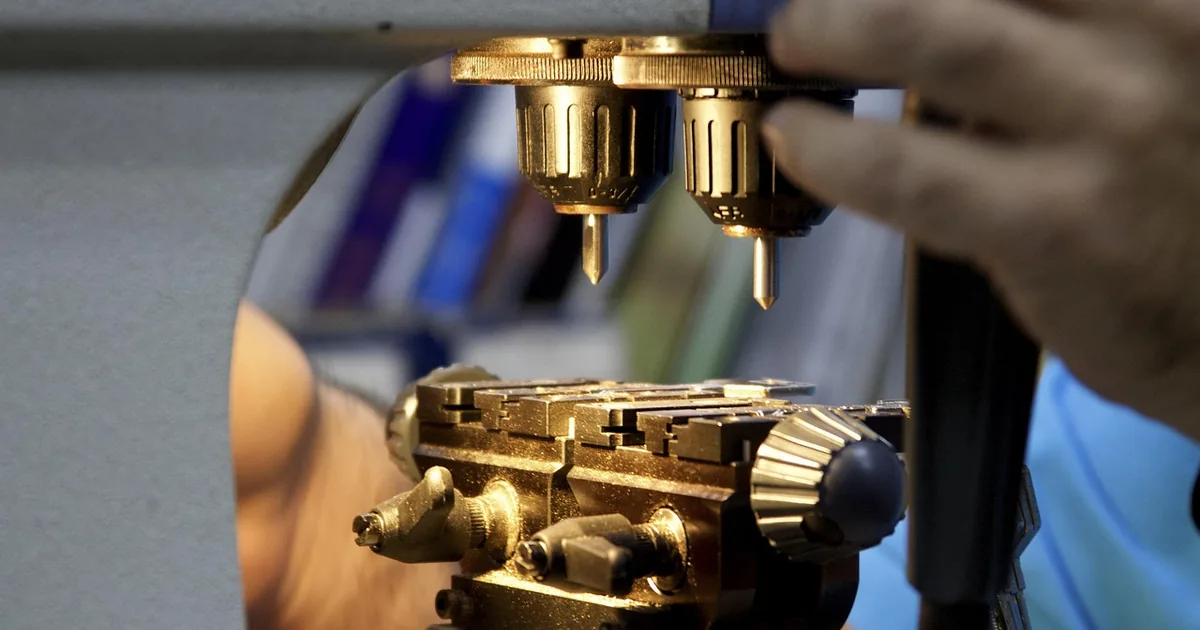 Key cutting machine with two drill bits above a clamped key blank