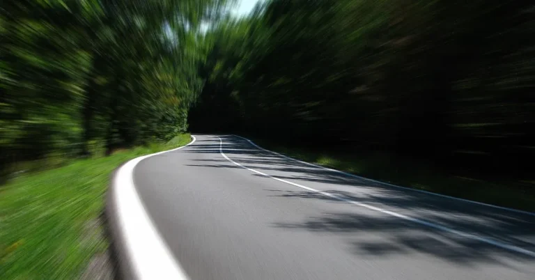 Motion-blurred curving road through green trees