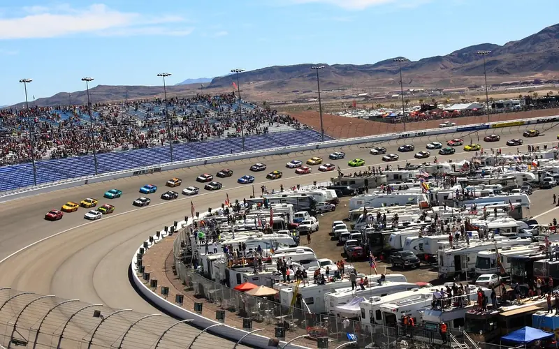 NASCAR race cars competing on track in front of a full grandstand crowd NASCAR race cars competing on track in front of a full grandstand crowd