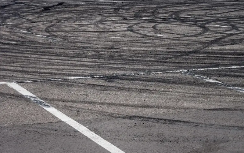 Black tyre marks on circuit asphalt in front of red and white barriers