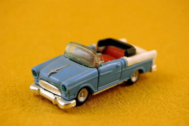 A small blue toy convertible on a yellow background