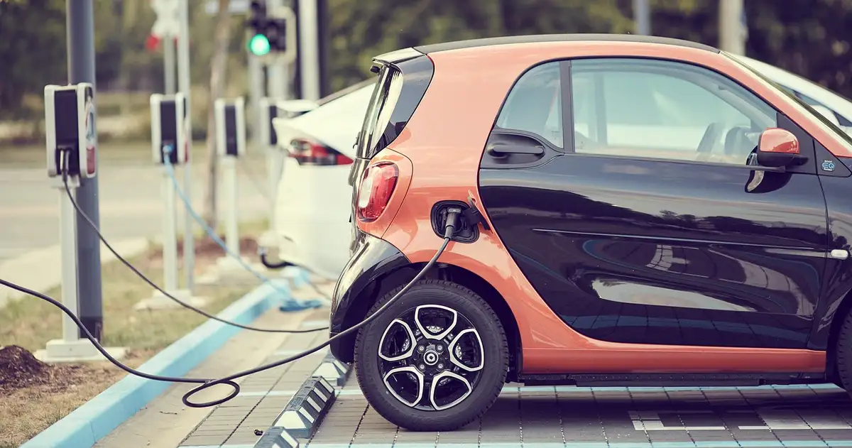 Small electric car plugged in at a public charging station