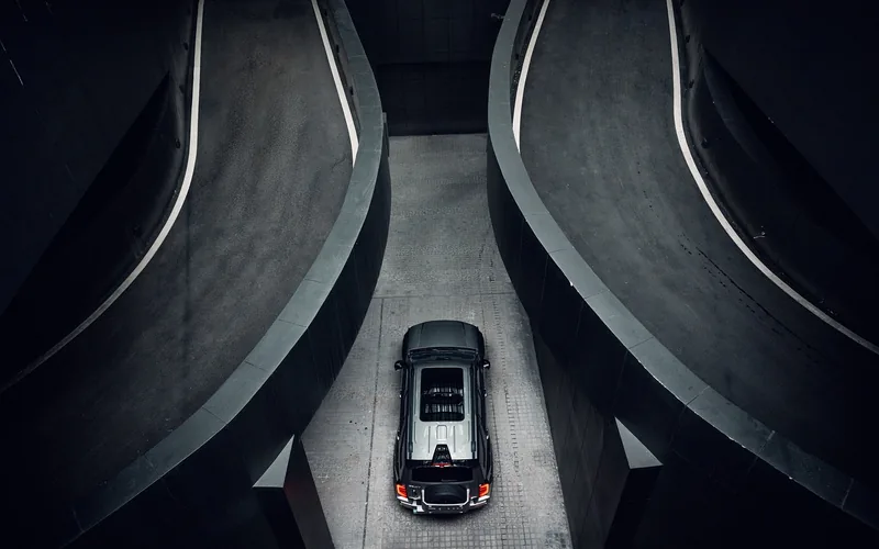 Dark SUV photographed from above between two curved parking ramps