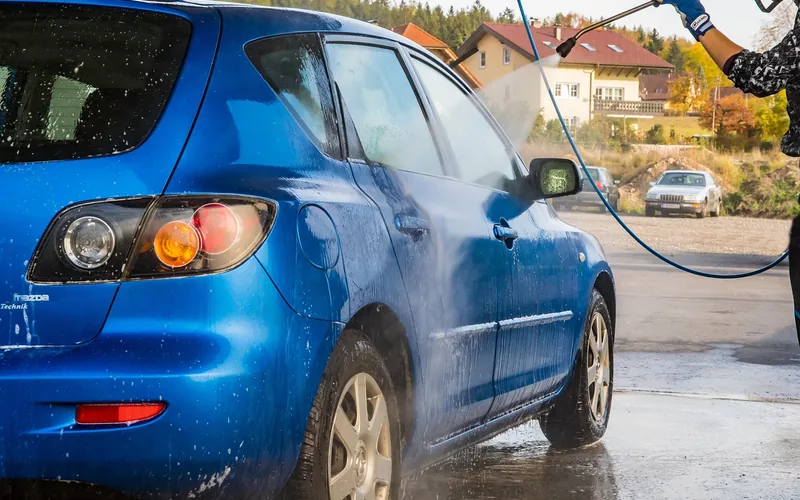 Tesla-style electric vehicle passing through an automatic foam car wash bay