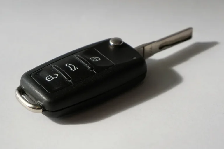 Black flip key with remote buttons on a light grey surface