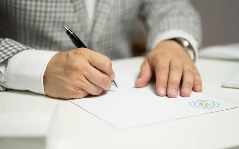 Reading a vehicle service contract carefully before signing Close-up of a hand signing a vehicle service contract document with a pen