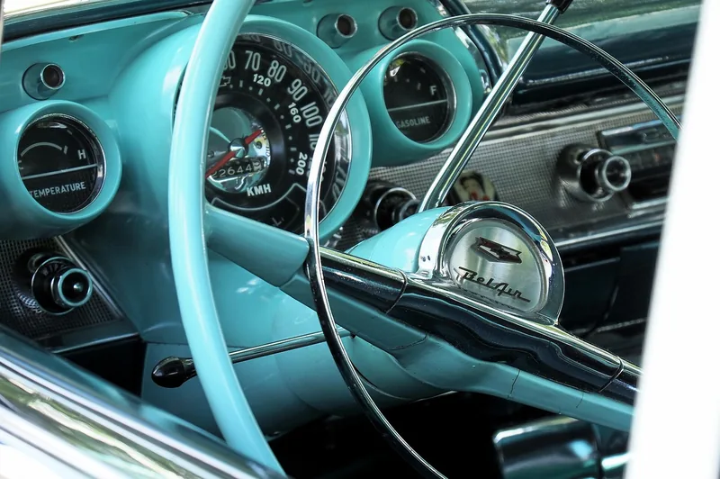 Steering wheel and round gauges on the dashboard of a vintage American car