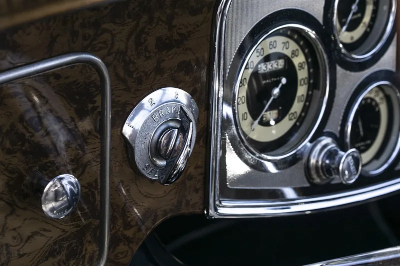 Chrome-ringed speedometer and ignition switch on a vintage car dashboard
