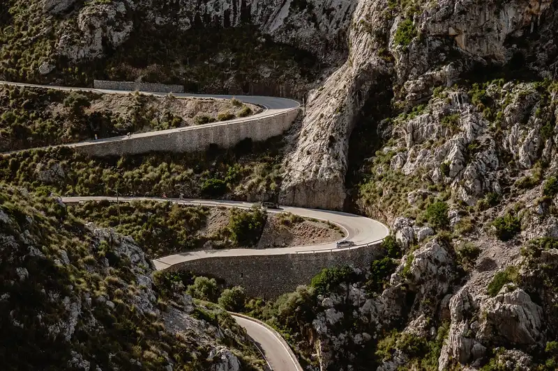 Winding mountain road with hairpin bends cut into a rock face