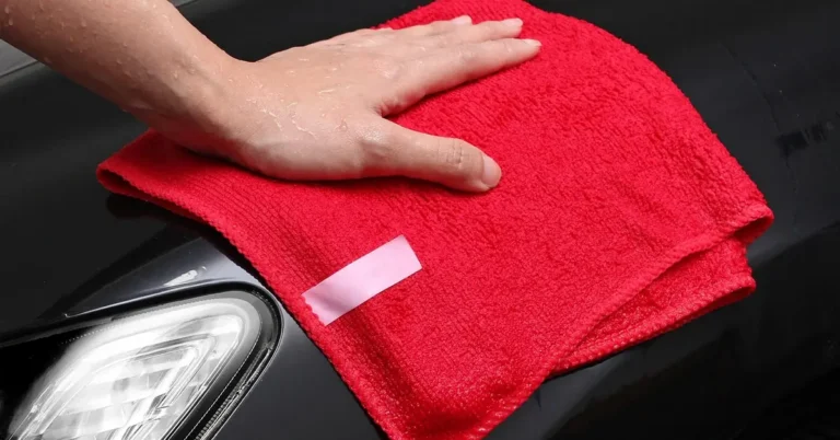 hand wiping a car headlight lens with a red microfiber cloth