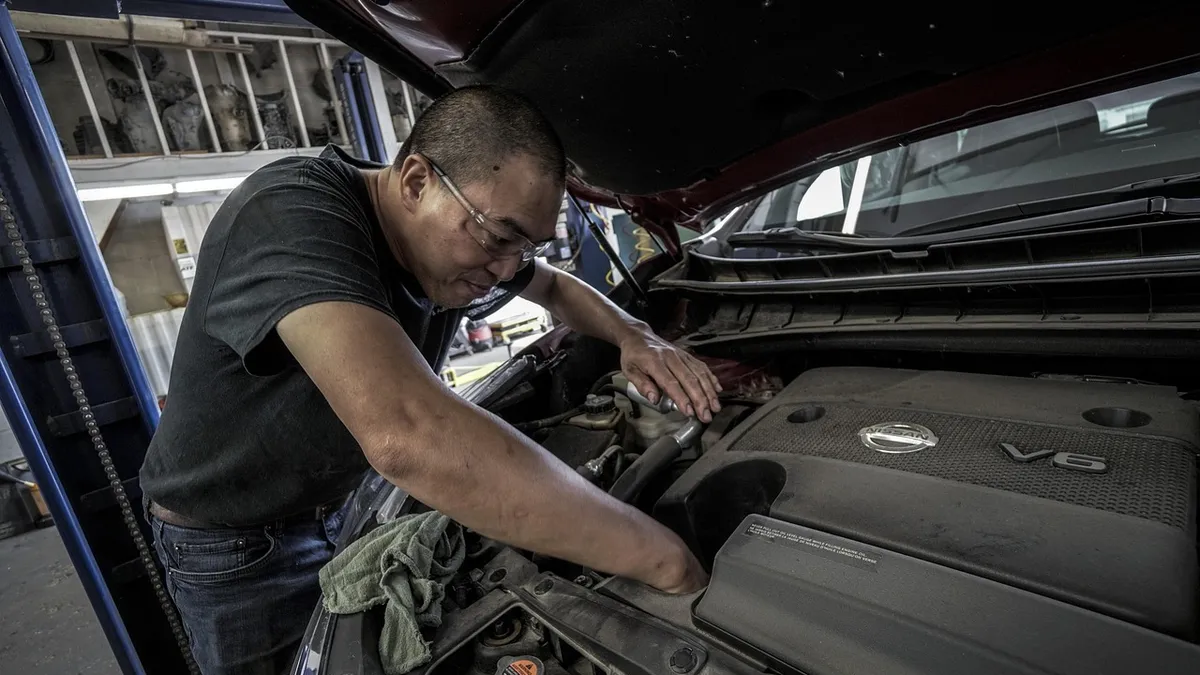 Auto repair technician working under the hood to complete repairs before an emissions retest