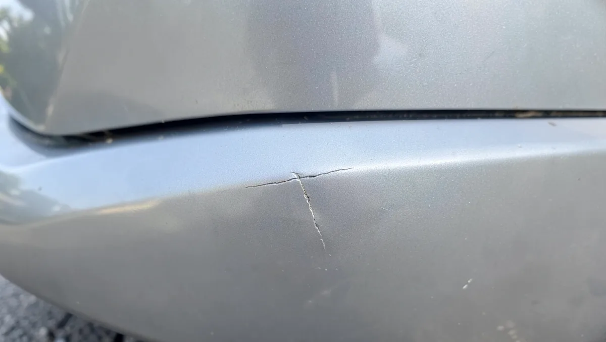 Close-up of a small scratch and crack in the paint on a rental car rear bumper
