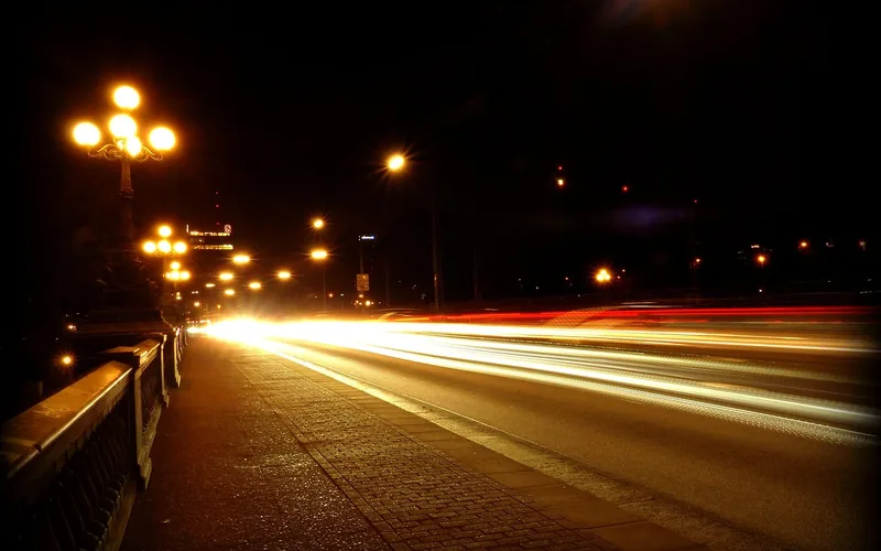Car driving at night with headlights illuminating the road