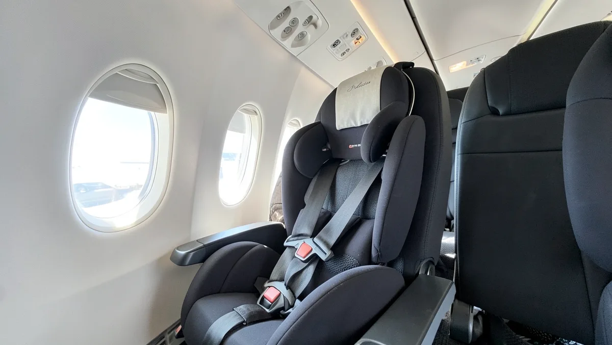 FAA-approved child car seat installed in an airplane window seat using the seatbelt