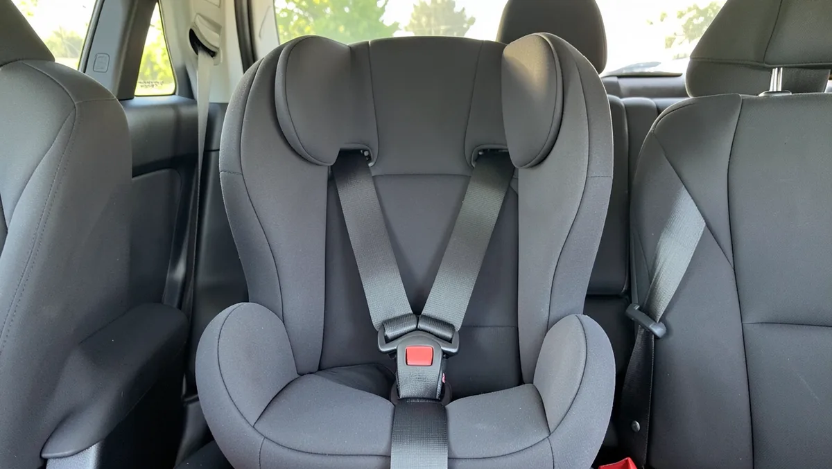 Forward-facing child car seat correctly installed in a car back seat with the five-point harness buckled