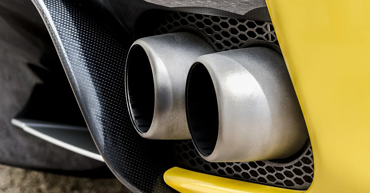 Close-up of two chrome exhaust tailpipe tips on the rear of a yellow car