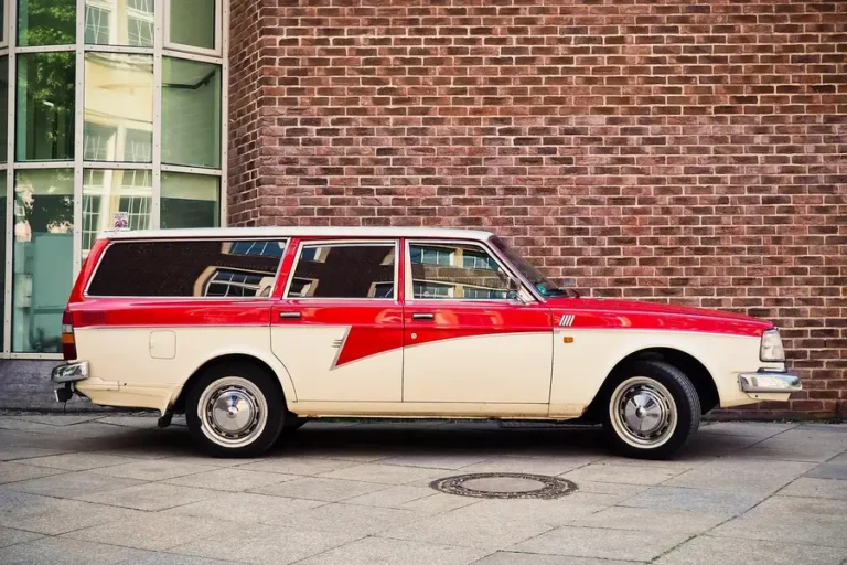 Red and cream station wagon parked beside a brick wall, side view showing its doors and windows