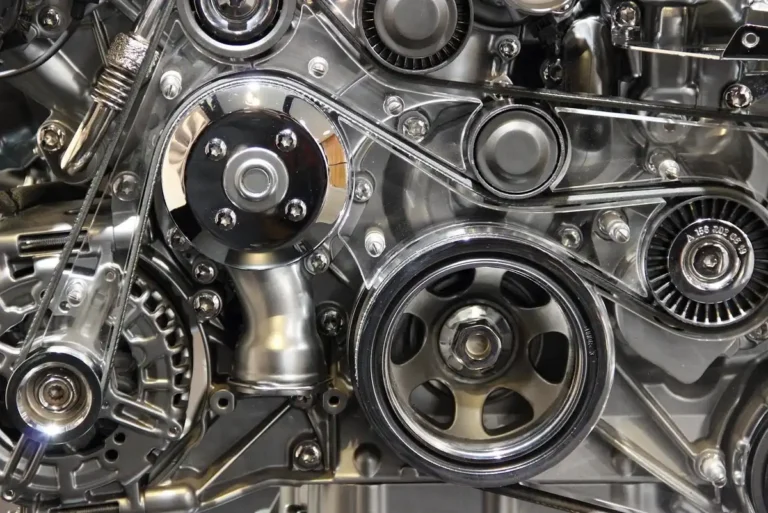 Close-up of an engine front with a drive belt, pulleys and a tensioner
