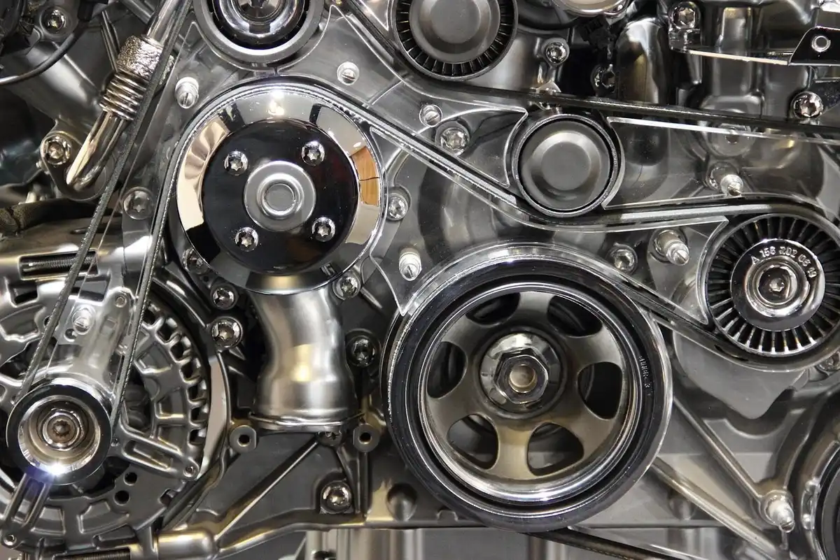 Close-up of an engine front with a drive belt, pulleys and a tensioner