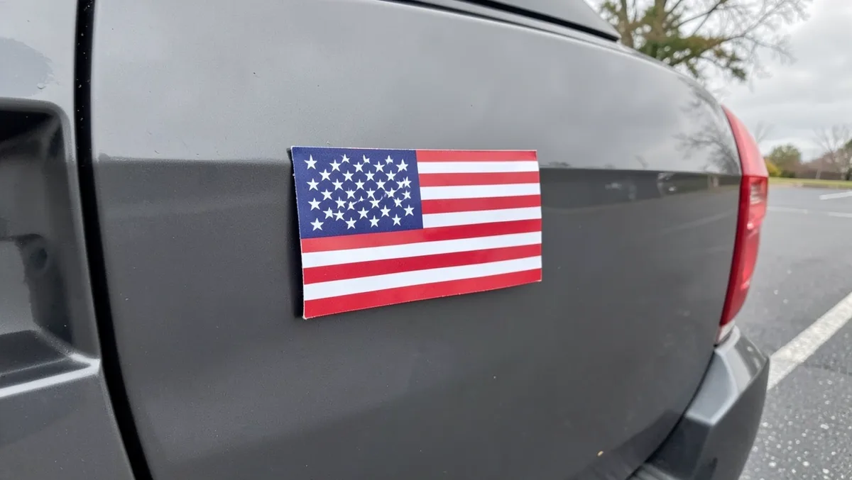Flat American flag magnet mounted on the rear door panel of a gray SUV